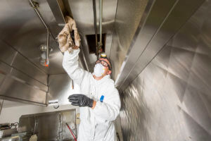 Commercial kitchen worker washing up at sink in professional kitchen Hood Cleaning Tampa